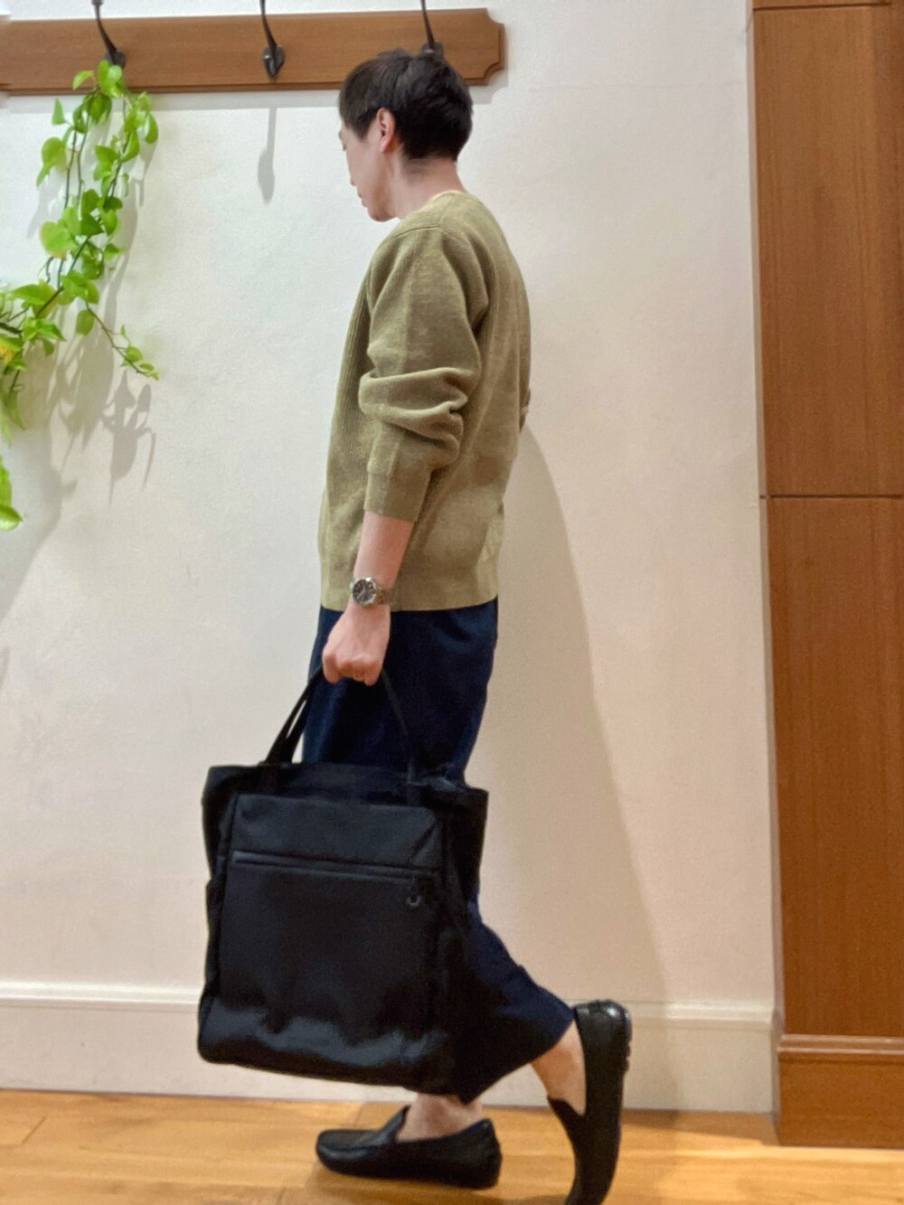 イエロー系のニット/セーター、ブルー系のデニムパンツ、ブラック系のトートバッグを着用したメンズの冬コーディネートの4枚目の写真