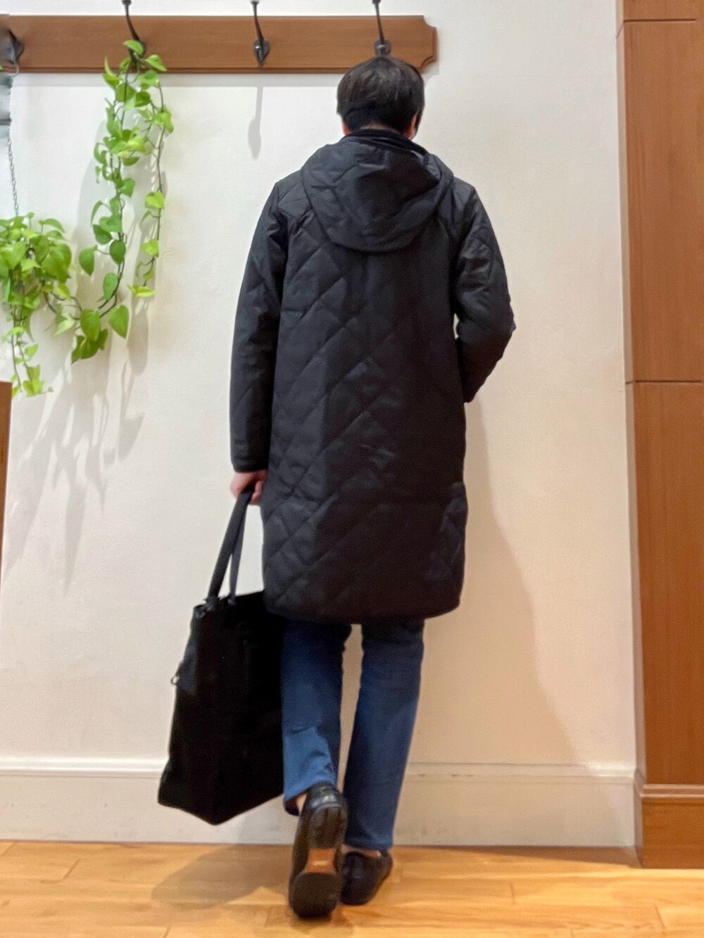 ブラック系のダウンジャケット/コート、オレンジ系のカーディガン/ボレロ、ブラック系のトートバッグを着用したメンズの秋コーディネートの6枚目の写真