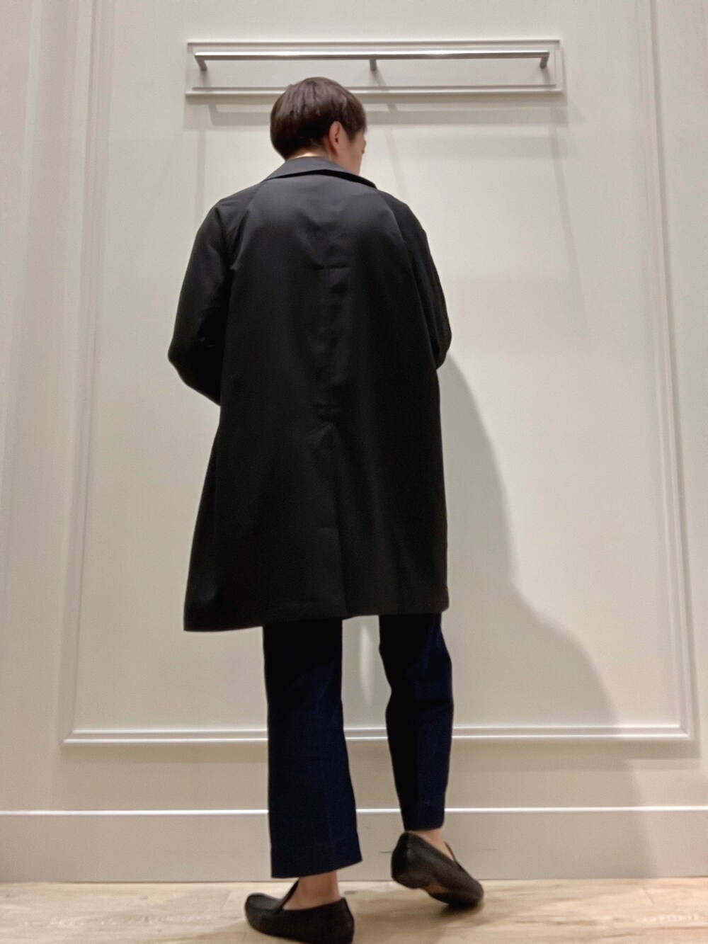 ブラック系のステンカラーコート、グリーン系のニット/セーターを着用したメンズの冬コーディネートの3枚目の写真