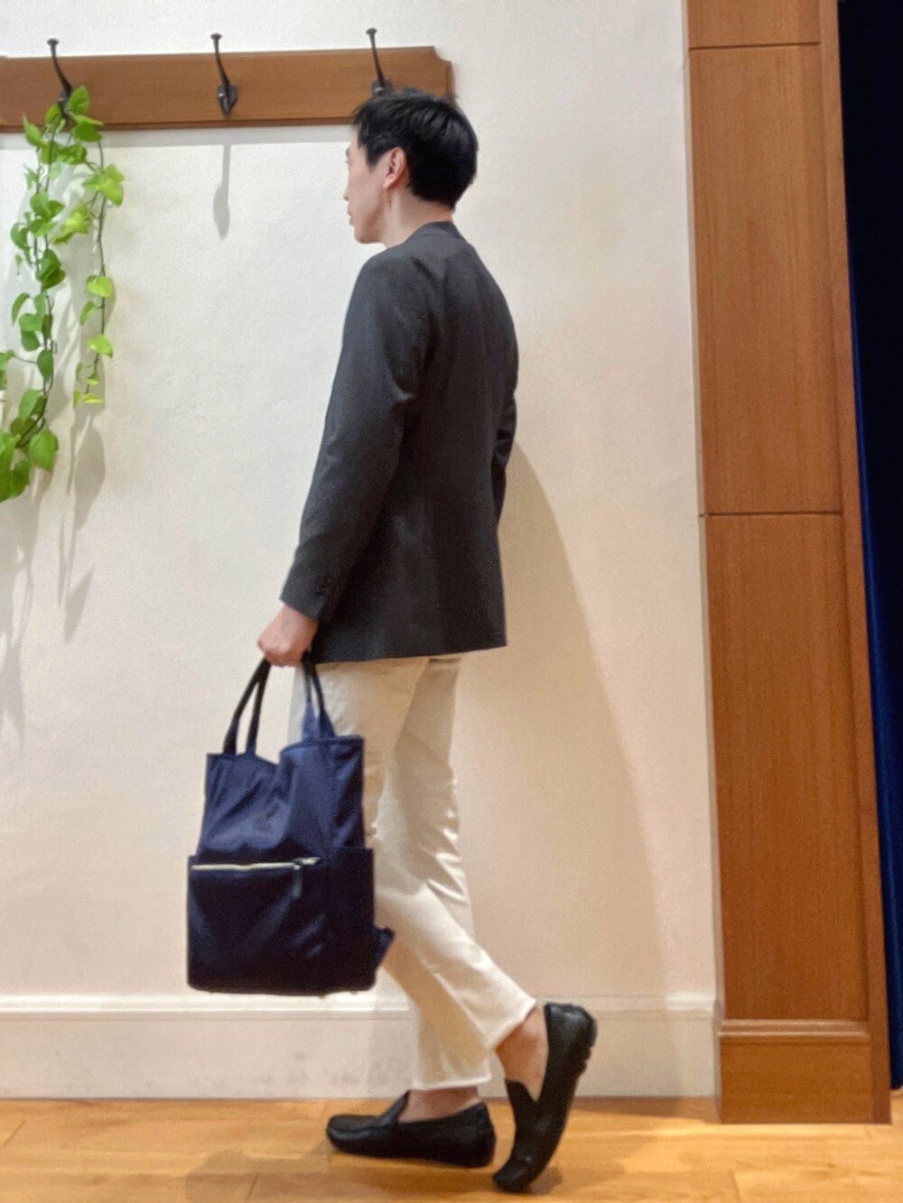 パープル系のニット/セーター、ホワイト系のチノパンツ、ブルー系のトートバッグを着用したメンズの秋コーディネートの3枚目の写真