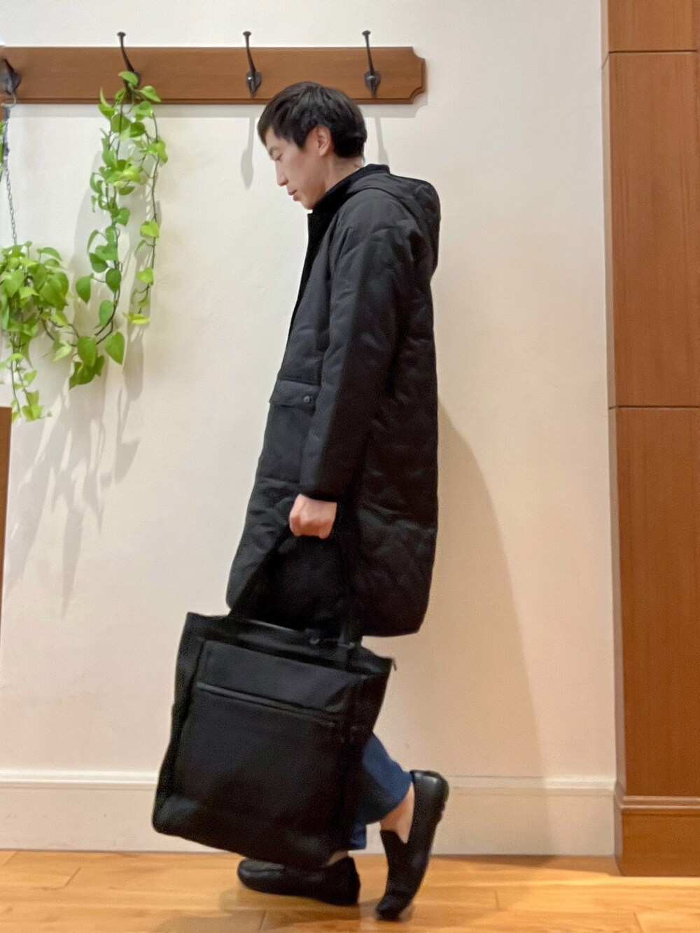 ブラック系のダウンジャケット/コート、オレンジ系のカーディガン/ボレロ、ブラック系のトートバッグを着用したメンズの秋コーディネートの4枚目の写真