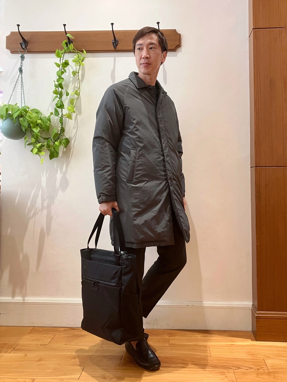 ブラック系のトートバッグ、ブラウン系のスラックス、グレー系のダウンジャケット/コートを着用したメンズの夏コーディネートの7枚目の写真