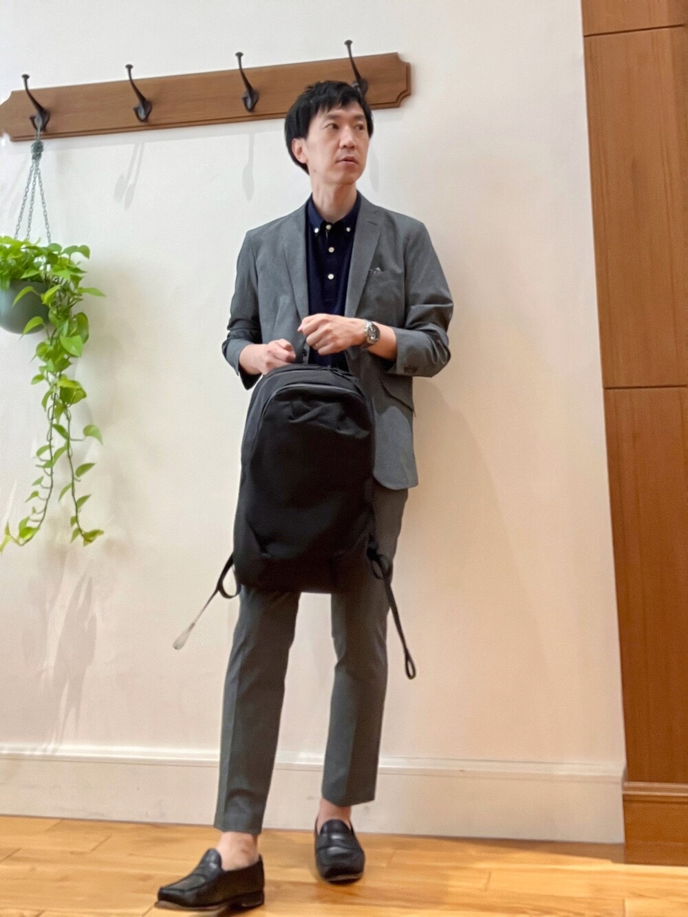 グレー系のテーラードジャケット、ブルー系のポロシャツ、ブラック系のバックパック/リュックを着用したメンズの春コーディネートの2枚目の写真