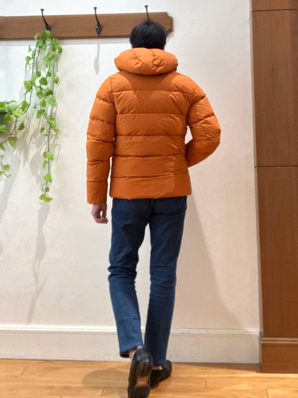 ブルー系のデニムパンツ、ベージュ系のニット/セーター、オレンジ系のダウンジャケット/コートを着用したメンズの冬コーディネートの5枚目の写真
