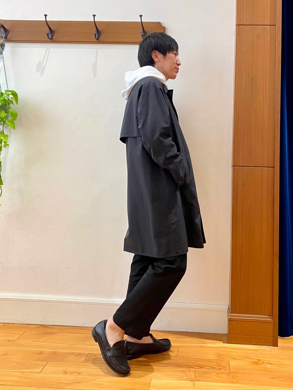 ブラック系のステンカラーコート、グレー系のパーカーを着用したメンズの冬コーディネートの7枚目の写真