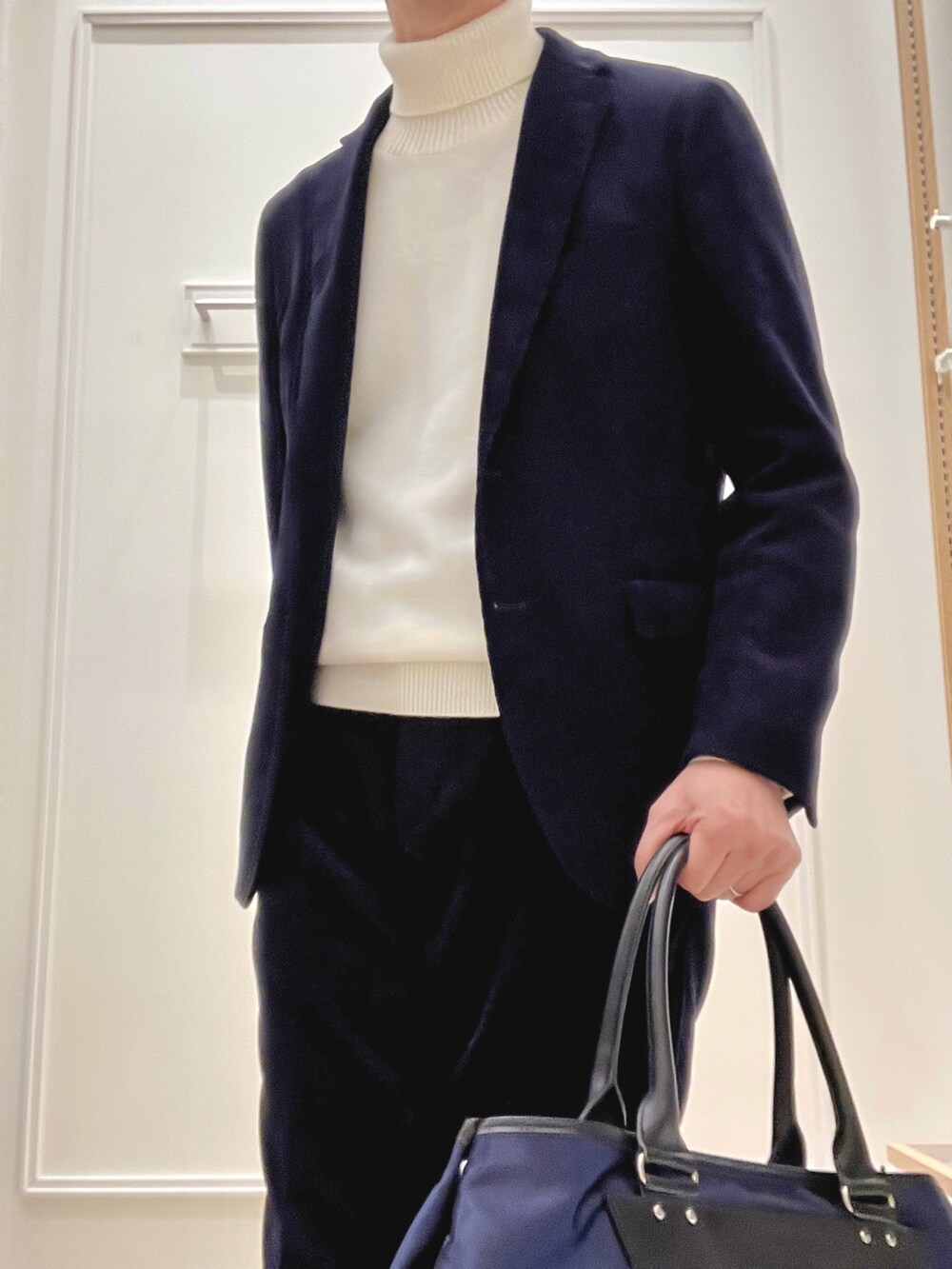 ホワイト系のニット/セーター、ブルー系のトートバッグを着用したメンズの冬コーディネートの6枚目の写真