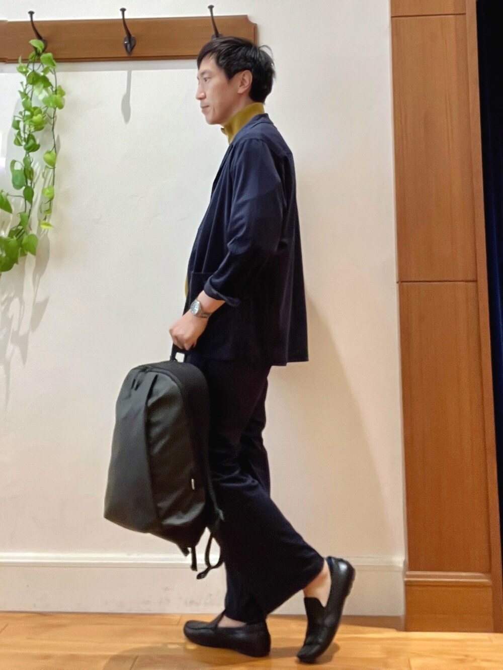 ブルー系のシャツ/ブラウス、イエロー系のニット/セーター、グレー系のバックパック/リュックを着用したメンズの秋コーディネートの4枚目の写真