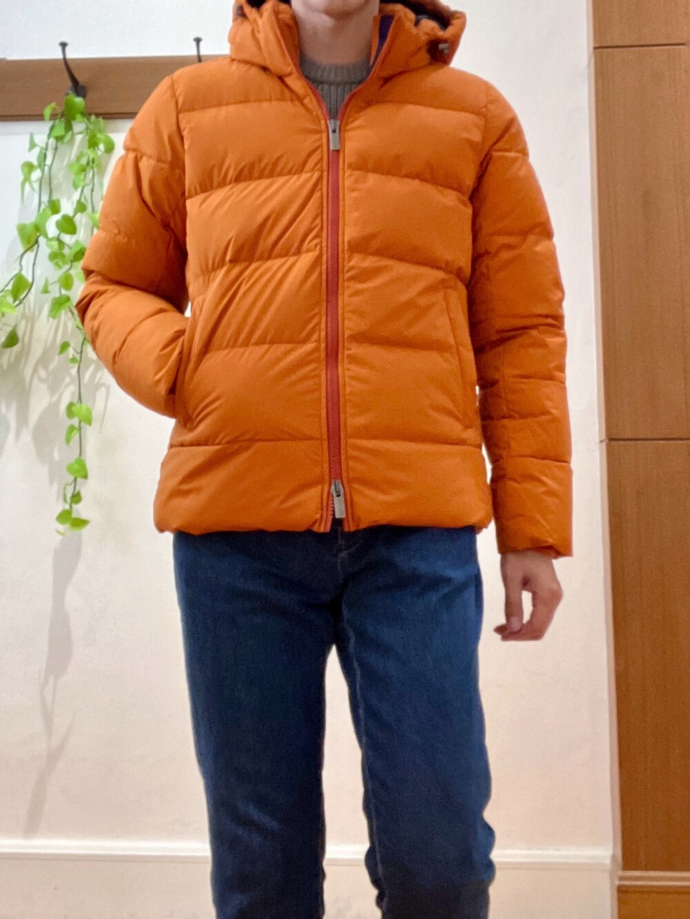 ブルー系のデニムパンツ、ベージュ系のニット/セーター、オレンジ系のダウンジャケット/コートを着用したメンズの冬コーディネートの9枚目の写真