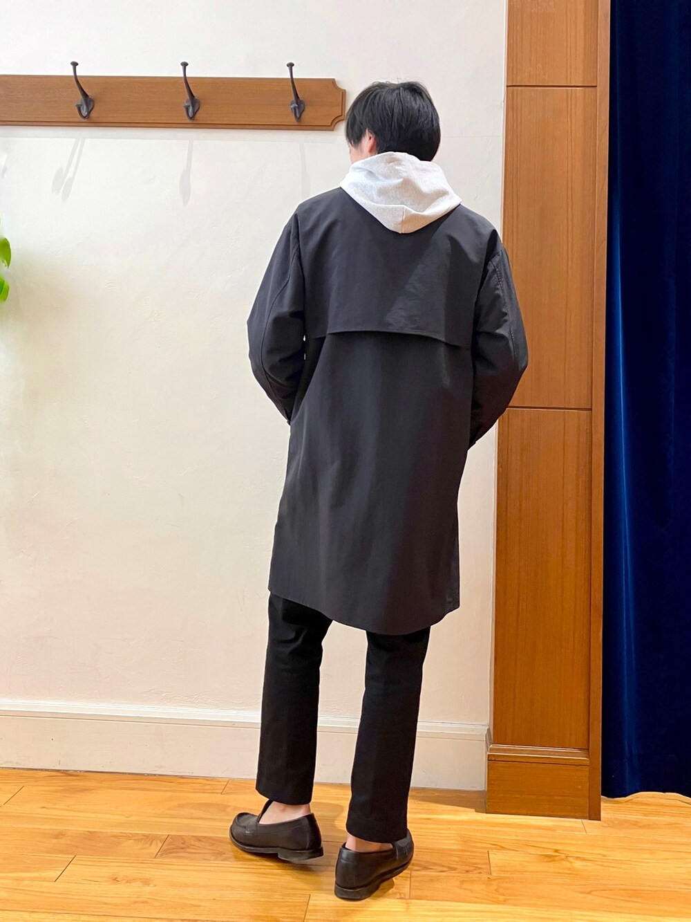 ブラック系のステンカラーコート、グレー系のパーカーを着用したメンズの冬コーディネートの6枚目の写真