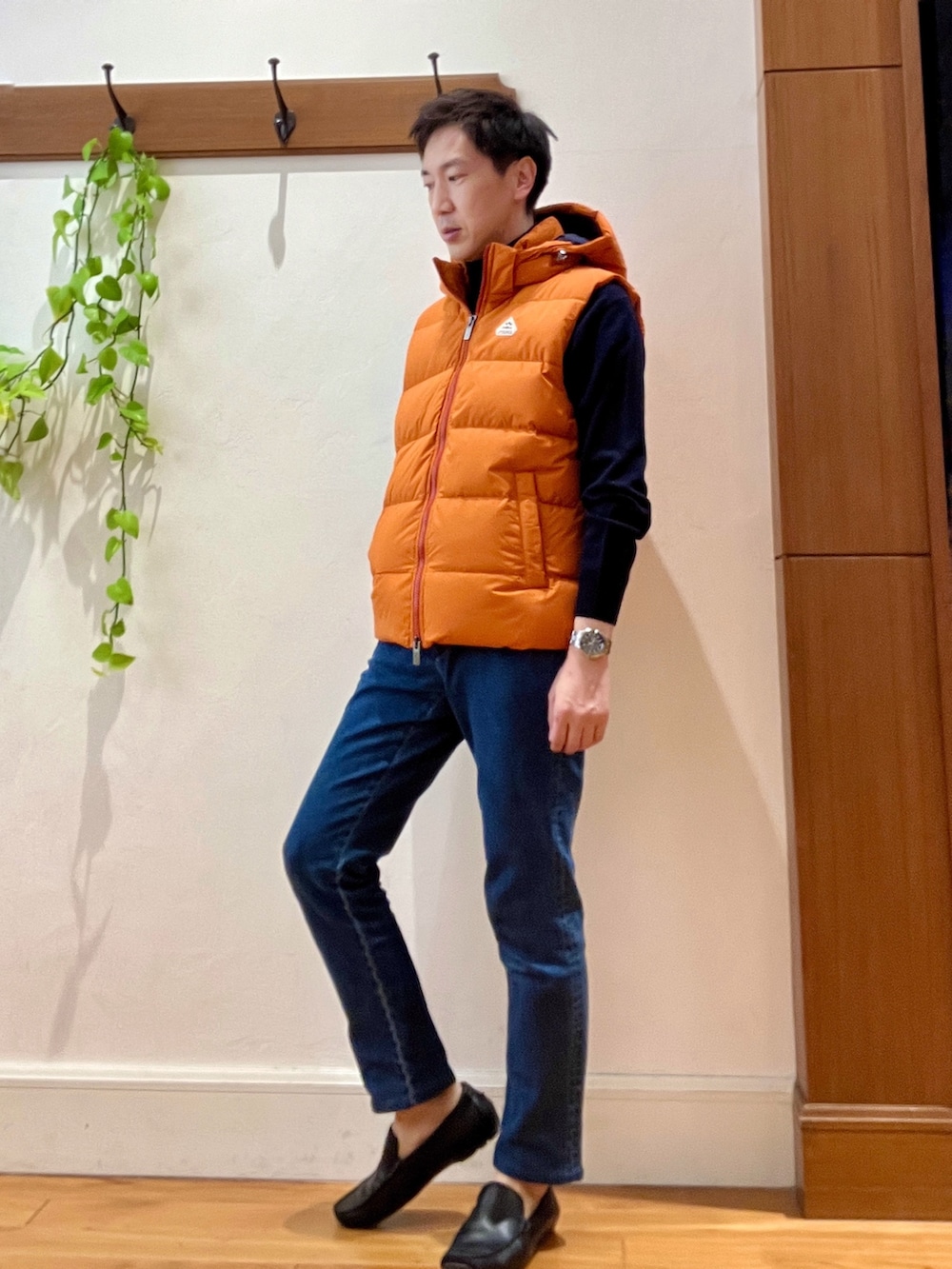 ブルー系のデニムパンツ、ブルー系のニット/セーター、オレンジ系のダウンベストを着用したメンズの冬コーディネートの3枚目の写真
