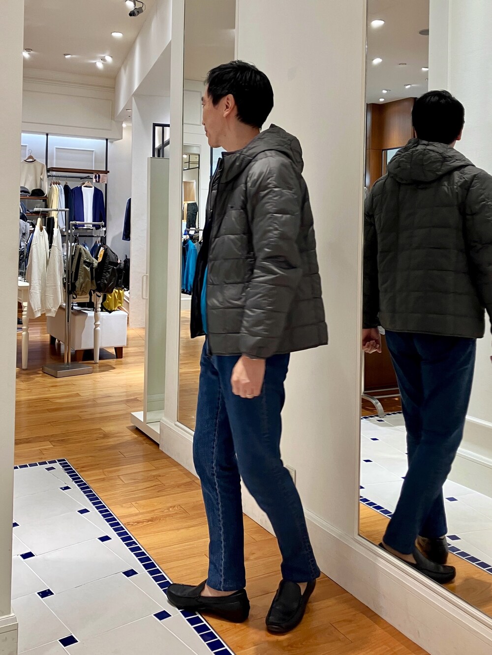 ブルー系のカーディガン/ボレロ、グレー系のダウンジャケット/コート、ブルー系のデニムパンツを着用したメンズの秋コーディネートの3枚目の写真