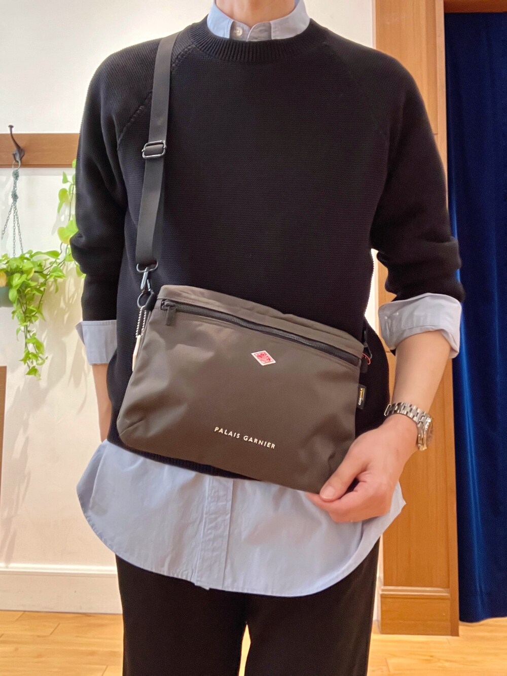 ブラック系のニット/セーター、グレー系のショルダーバッグ、ブルー系のシャツ/ブラウスを着用したメンズの春コーディネートの9枚目の写真