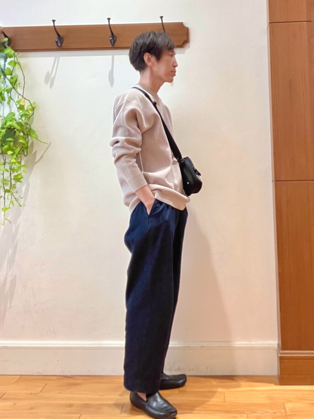 ブルー系のデニムパンツ、ブラック系のショルダーバッグ、ベージュ系のニット/セーターを着用したメンズの秋コーディネートの6枚目の写真