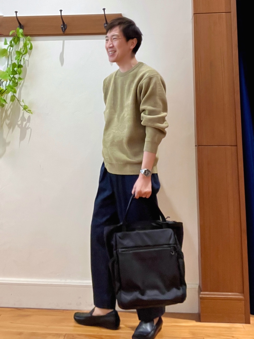 イエロー系のニット/セーター、ブルー系のデニムパンツ、ブラック系のトートバッグを着用したメンズの冬コーディネートの3枚目の写真