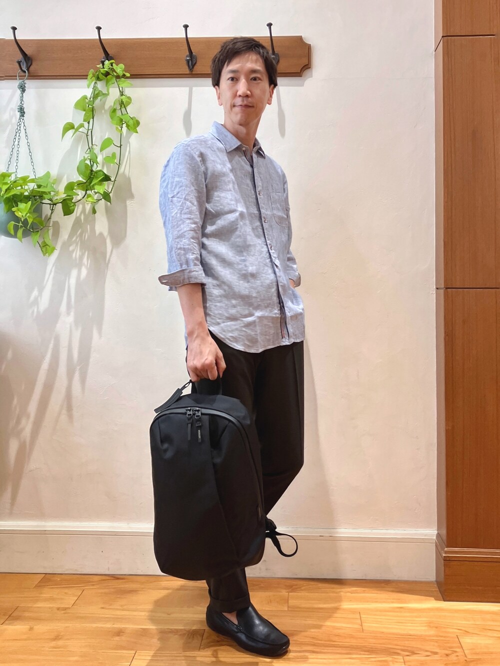 ブルー系のシャツ/ブラウス、ブラウン系のスラックス、ブラック系のバックパック/リュックを着用したメンズの春コーディネートの6枚目の写真