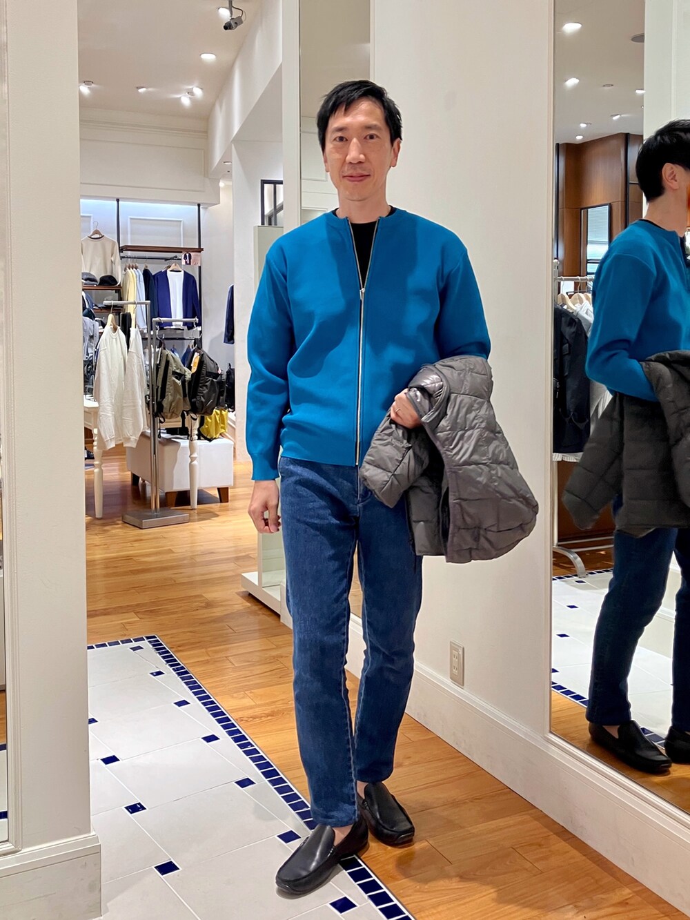 ブルー系のカーディガン/ボレロ、グレー系のダウンジャケット/コート、ブルー系のデニムパンツを着用したメンズの秋コーディネートの8枚目の写真