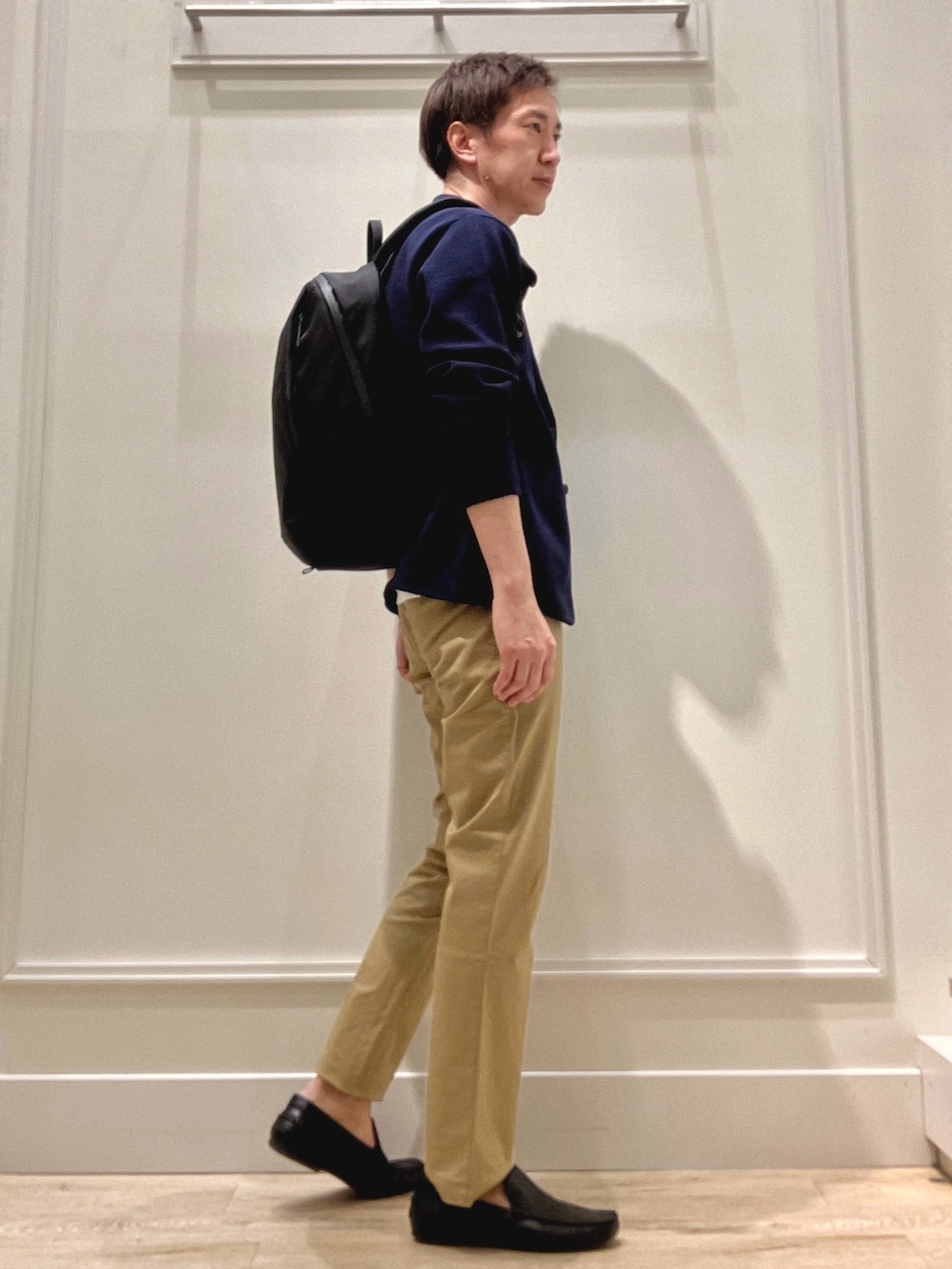 ベージュ系のチノパンツ、ブラック系のバックパック/リュック、ブルー系のカーディガン/ボレロを着用したメンズの冬コーディネートの7枚目の写真