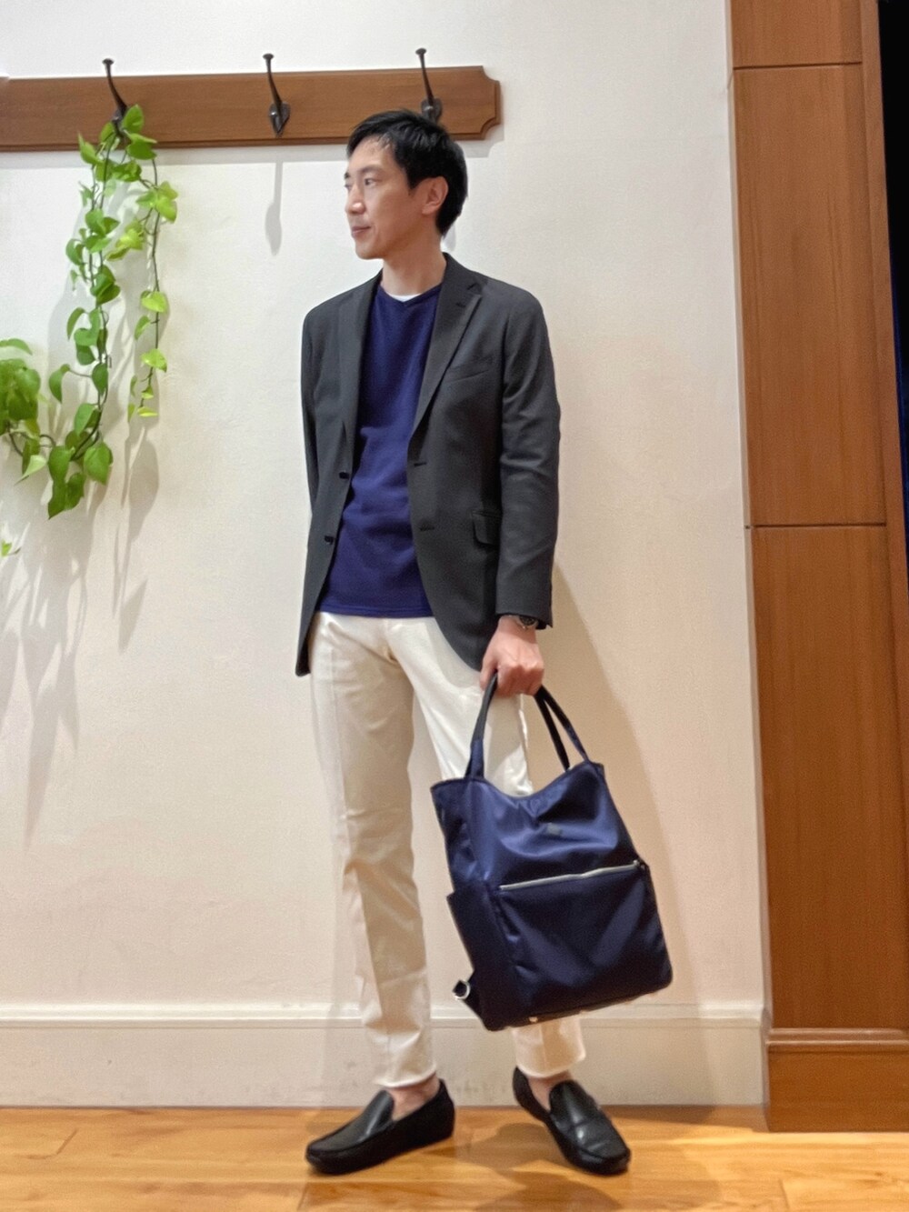 パープル系のニット/セーター、ホワイト系のチノパンツ、ブルー系のトートバッグを着用したメンズの秋コーディネートの6枚目の写真