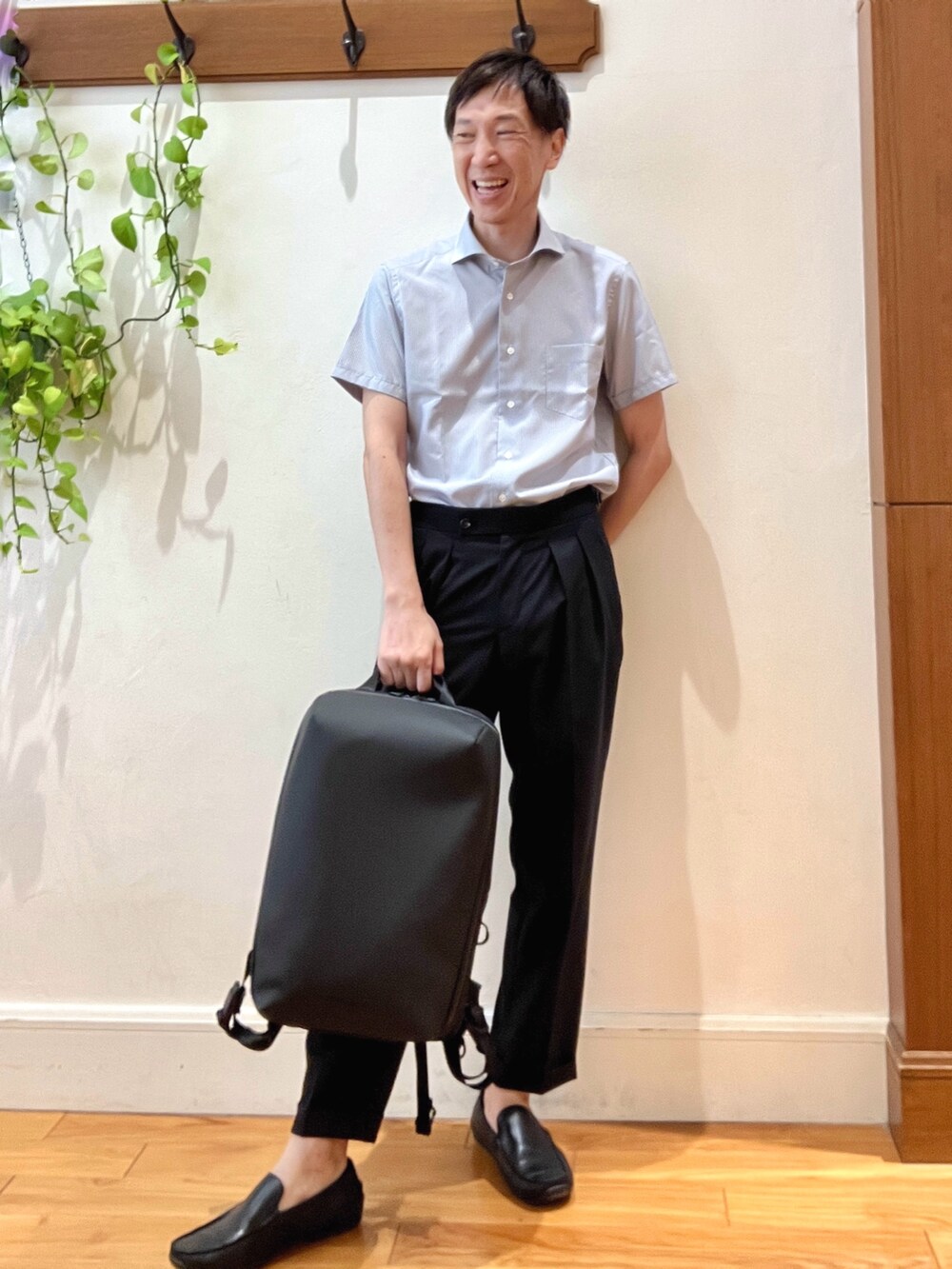 ブラック系のスラックス、ブルー系のビジネスシャツ、ブラック系のバックパック/リュックを着用したメンズの夏コーディネートの7枚目の写真