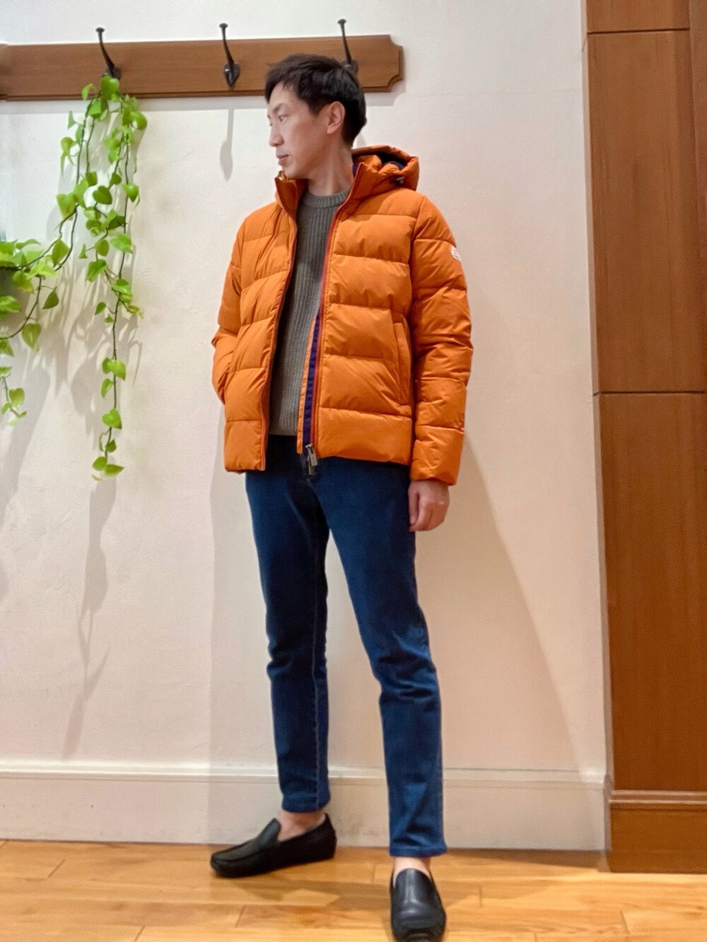 ブルー系のデニムパンツ、ベージュ系のニット/セーター、オレンジ系のダウンジャケット/コートを着用したメンズの冬コーディネートの2枚目の写真