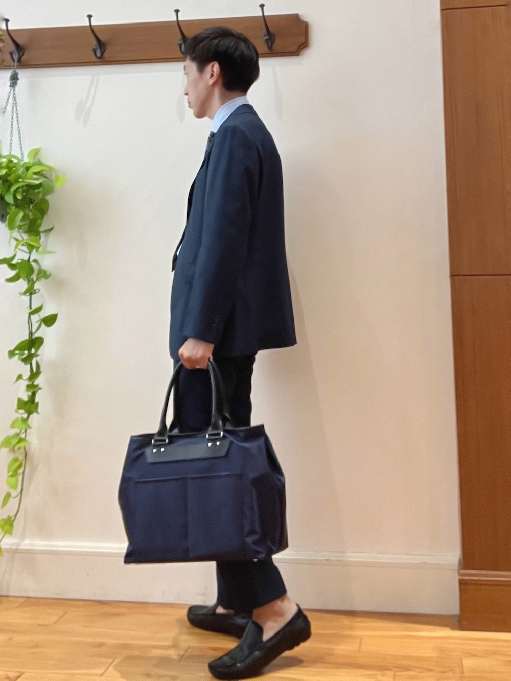 ブラック系のトートバッグ、ブルー系のスラックス、ベージュ系のネクタイを着用したメンズの秋コーディネートの3枚目の写真