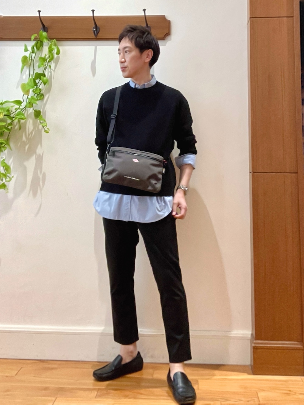 ブラック系のニット/セーター、グレー系のショルダーバッグ、ブルー系のシャツ/ブラウスを着用したメンズの春コーディネートの2枚目の写真