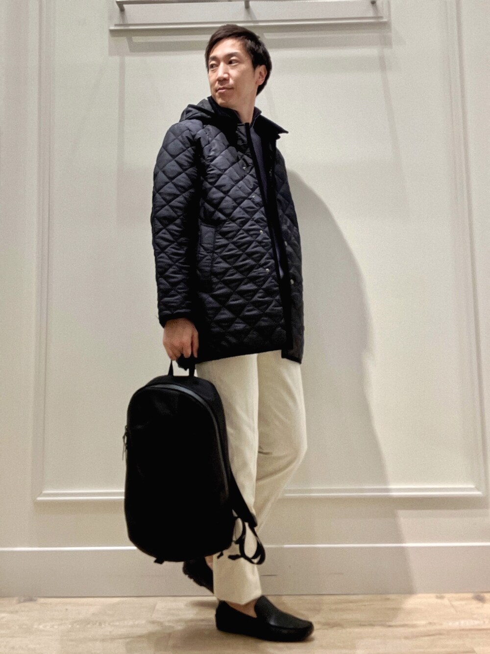 ブルー系のステンカラーコート、ブルー系のニット/セーター、ホワイト系のチノパンツを着用したメンズの冬コーディネートの8枚目の写真