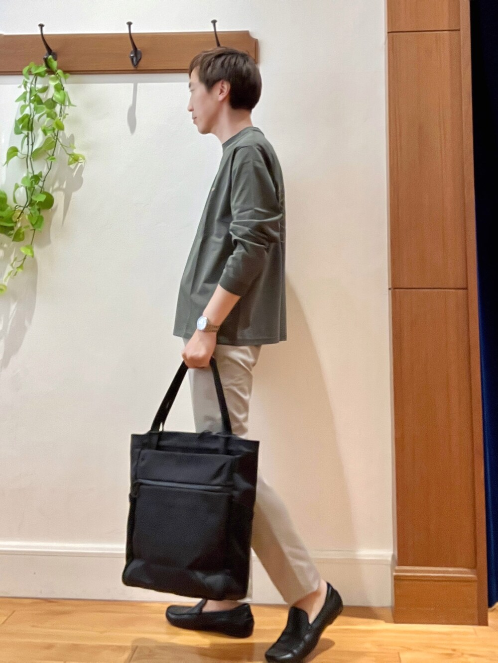 グリーン系のTシャツ/カットソー、グレー系のチノパンツ、ブラック系のトートバッグを着用したメンズの秋コーディネートの5枚目の写真