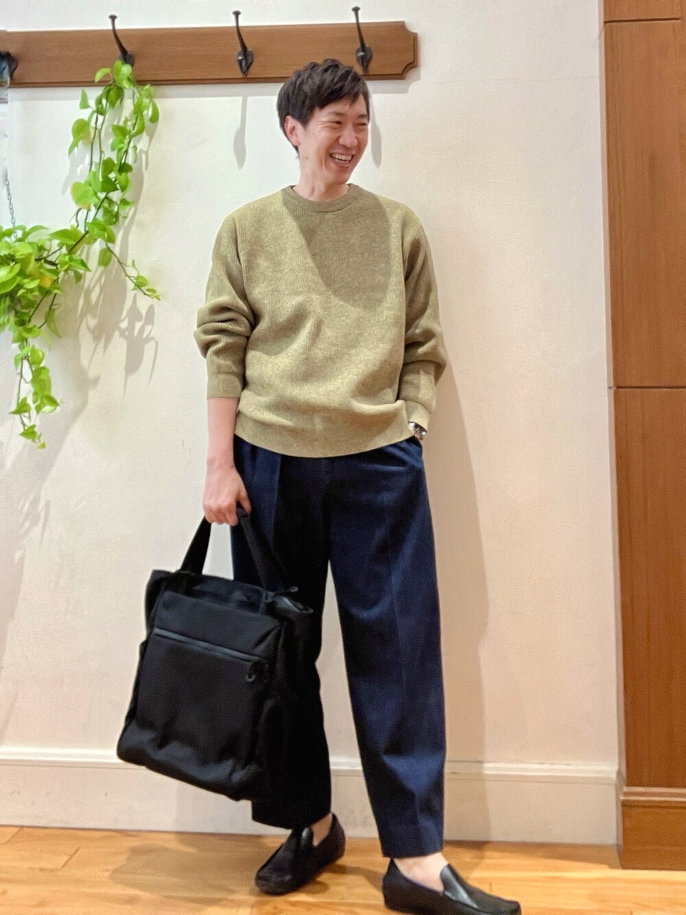 イエロー系のニット/セーター、ブルー系のデニムパンツ、ブラック系のトートバッグを着用したメンズの冬コーディネートの7枚目の写真