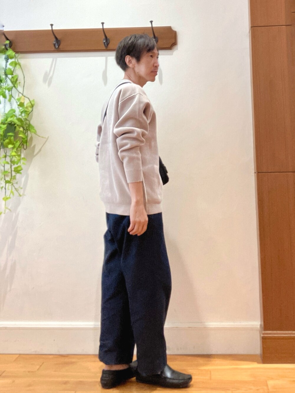 ブルー系のデニムパンツ、ブラック系のショルダーバッグ、ベージュ系のニット/セーターを着用したメンズの秋コーディネートの5枚目の写真