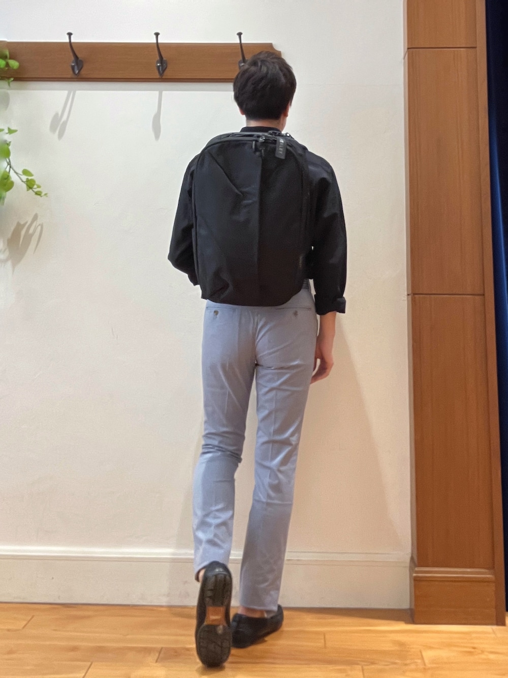 ブラック系のシャツ/ブラウス、ブルー系のチノパンツ、ブラック系のバックパック/リュックを着用したメンズの春コーディネートの5枚目の写真