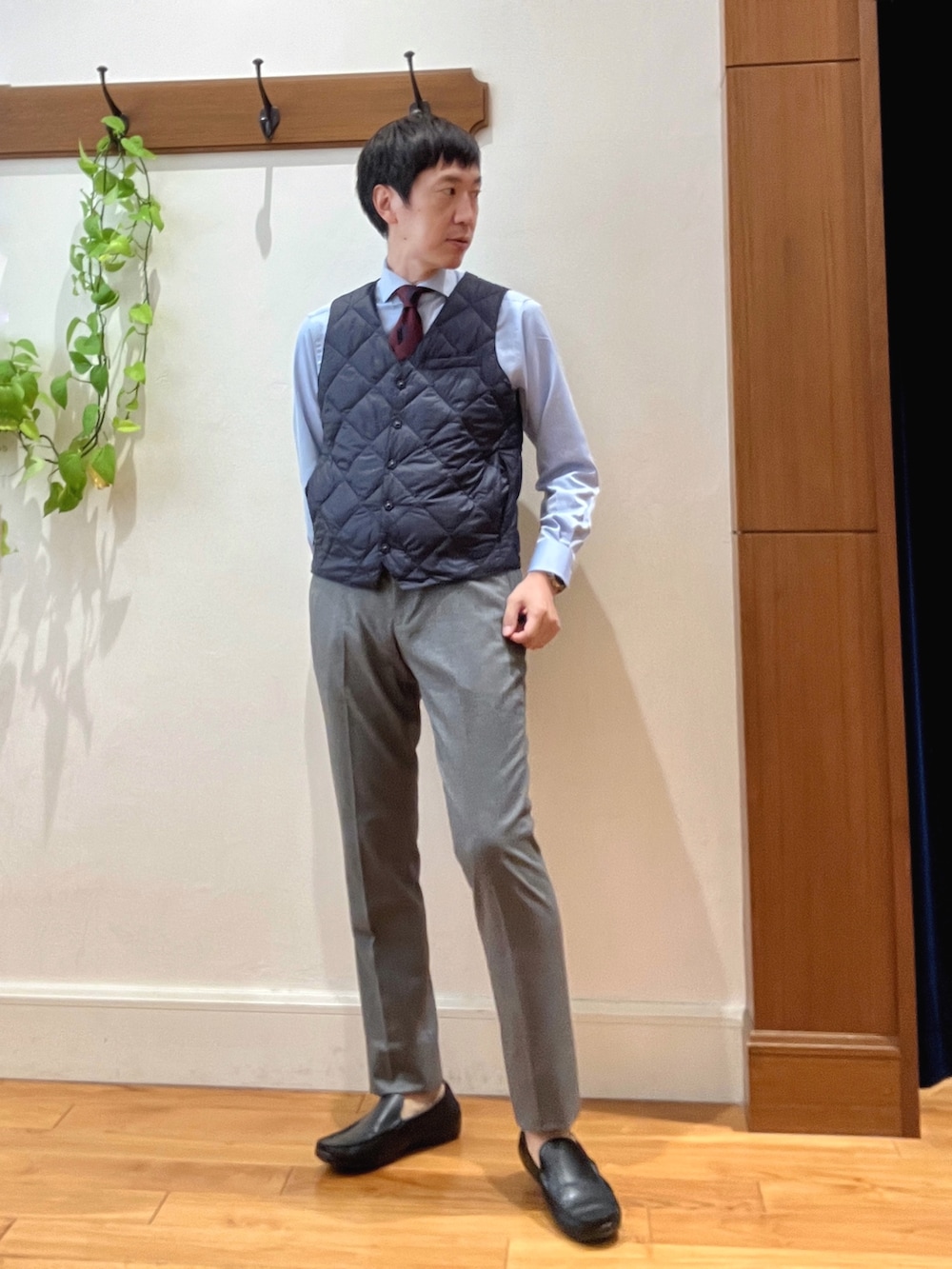 グレー系のその他パンツ、ブルー系のビジネスシャツ、ブルー系のダウンベストを着用したメンズの秋コーディネートの2枚目の写真