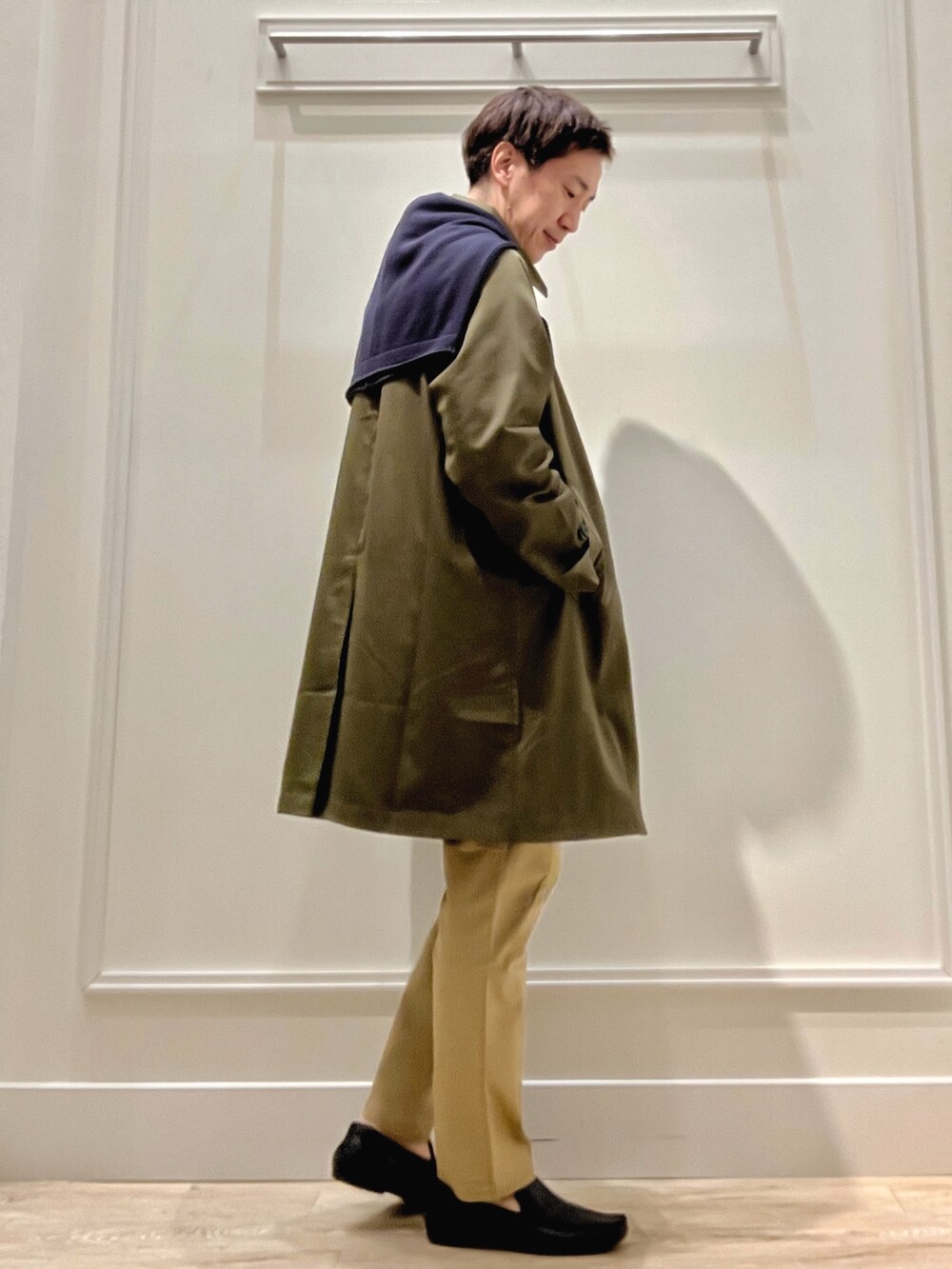 グリーン系のステンカラーコート、ベージュ系のチノパンツ、ブルー系のカーディガン/ボレロを着用したメンズの冬コーディネートの5枚目の写真