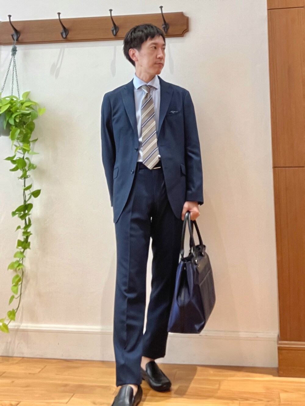 ブラック系のトートバッグ、ブルー系のスラックス、ベージュ系のネクタイを着用したメンズの秋コーディネートの2枚目の写真