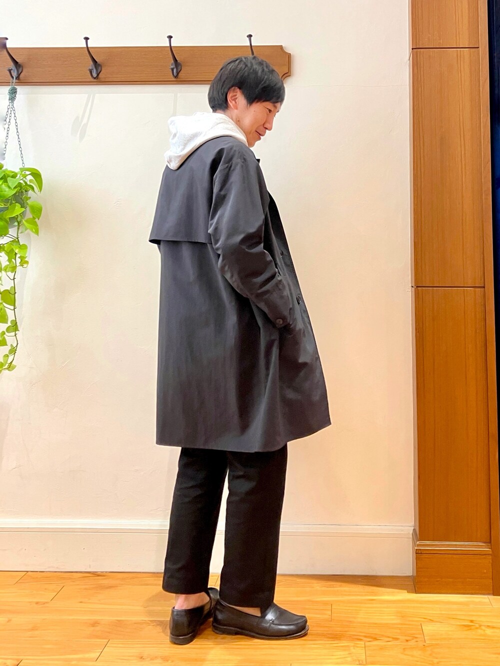 ブラック系のステンカラーコート、グレー系のパーカーを着用したメンズの冬コーディネートの5枚目の写真