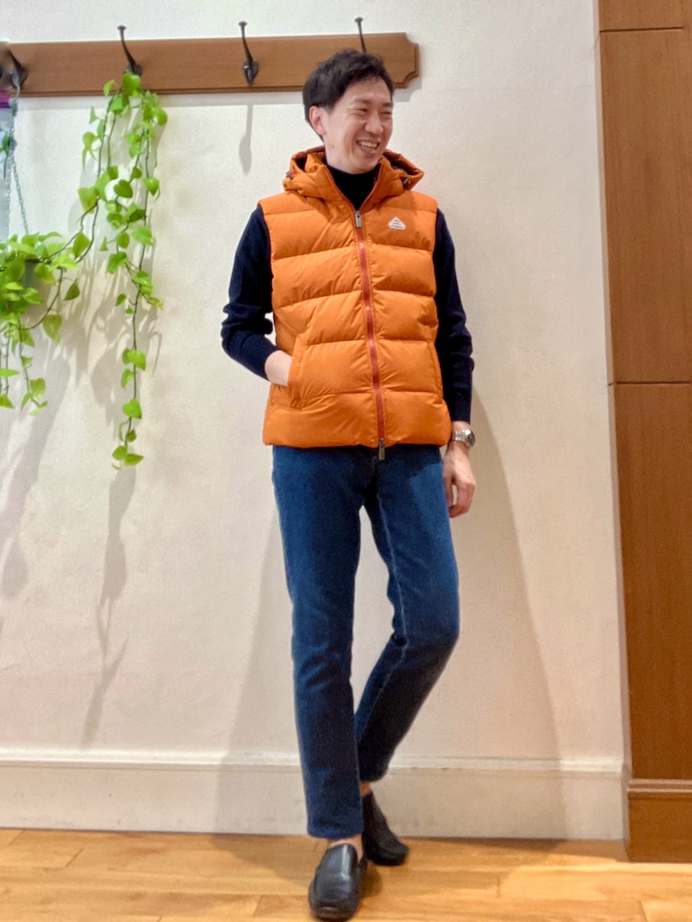 ブルー系のデニムパンツ、ブルー系のニット/セーター、オレンジ系のダウンベストを着用したメンズの冬コーディネートの7枚目の写真