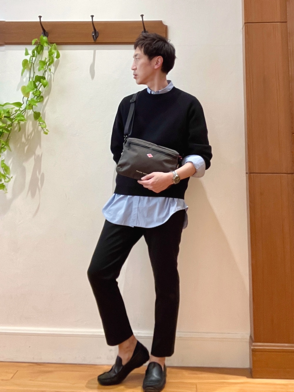 ブラック系のニット/セーター、グレー系のショルダーバッグ、ブルー系のシャツ/ブラウスを着用したメンズの春コーディネートの3枚目の写真