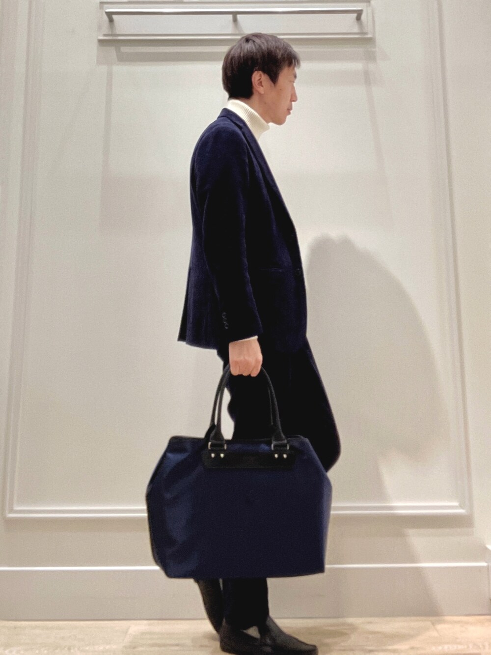 ホワイト系のニット/セーター、ブルー系のトートバッグを着用したメンズの冬コーディネートの5枚目の写真