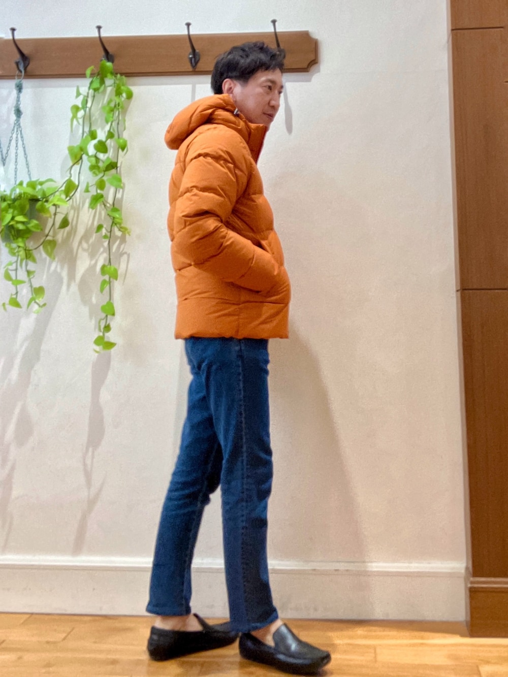 ブルー系のデニムパンツ、ベージュ系のニット/セーター、オレンジ系のダウンジャケット/コートを着用したメンズの冬コーディネートの6枚目の写真