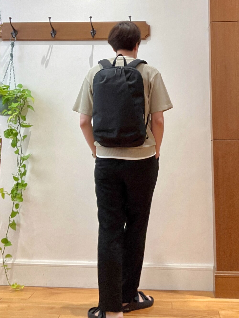 ブラック系のバックパック/リュック、ベージュ系のTシャツ/カットソー、ブラック系のサンダルを着用したメンズの夏コーディネートの4枚目の写真
