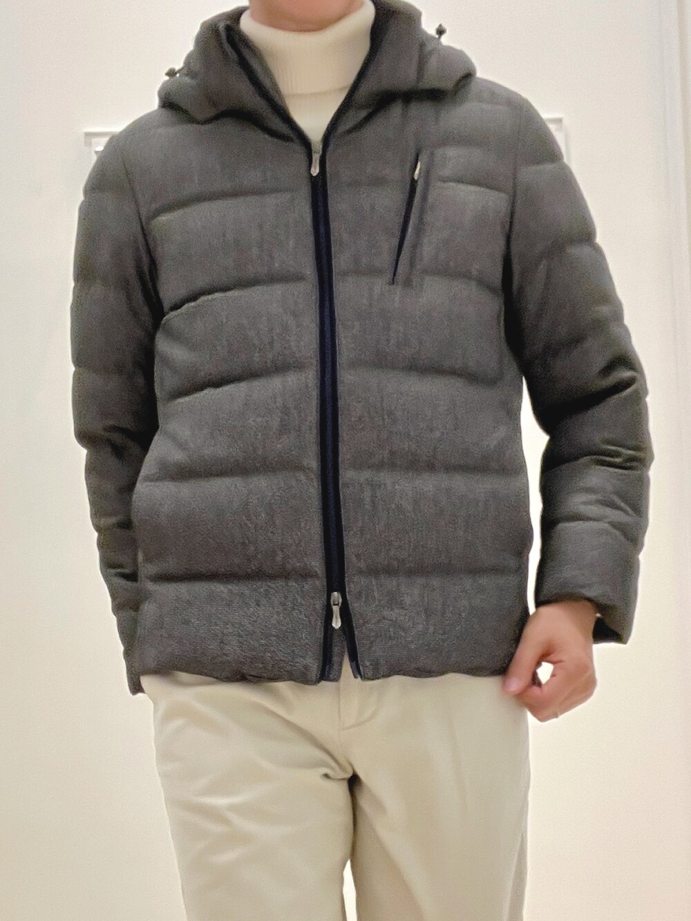 ホワイト系のニット/セーター、グレー系のダウンジャケット/コート、ホワイト系のチノパンツを着用したメンズの冬コーディネートの9枚目の写真