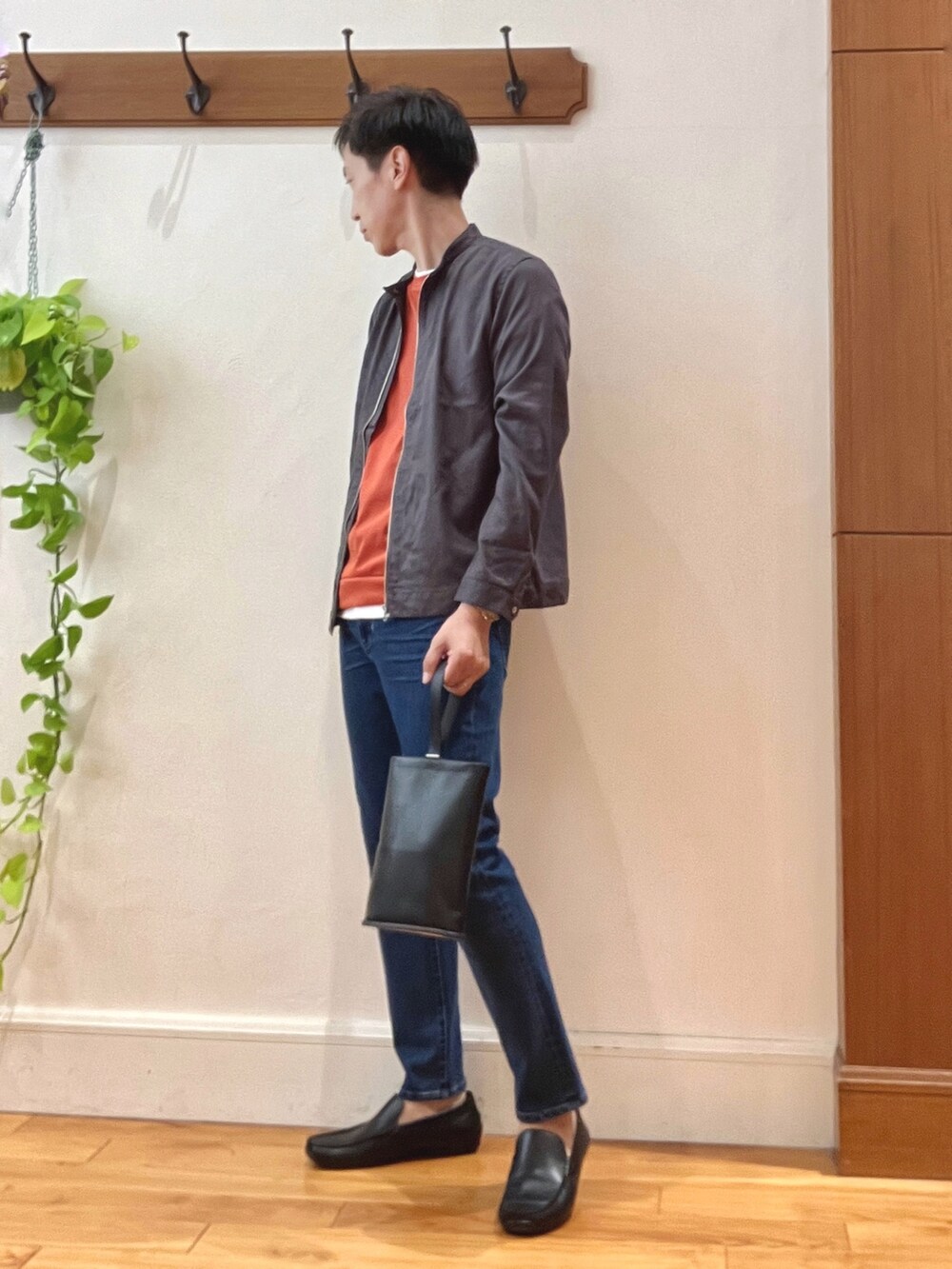 ブルー系のデニムパンツ、ブラック系のハンドバッグ、オレンジ系のTシャツ/カットソーを着用したメンズの秋コーディネートの3枚目の写真