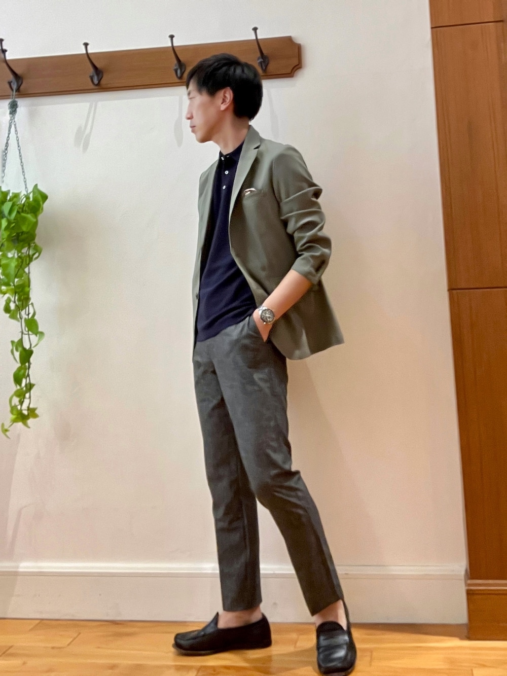 グリーン系のテーラードジャケット、ブラック系のポロシャツ、グレー系のその他パンツを着用したメンズの春コーディネートの3枚目の写真