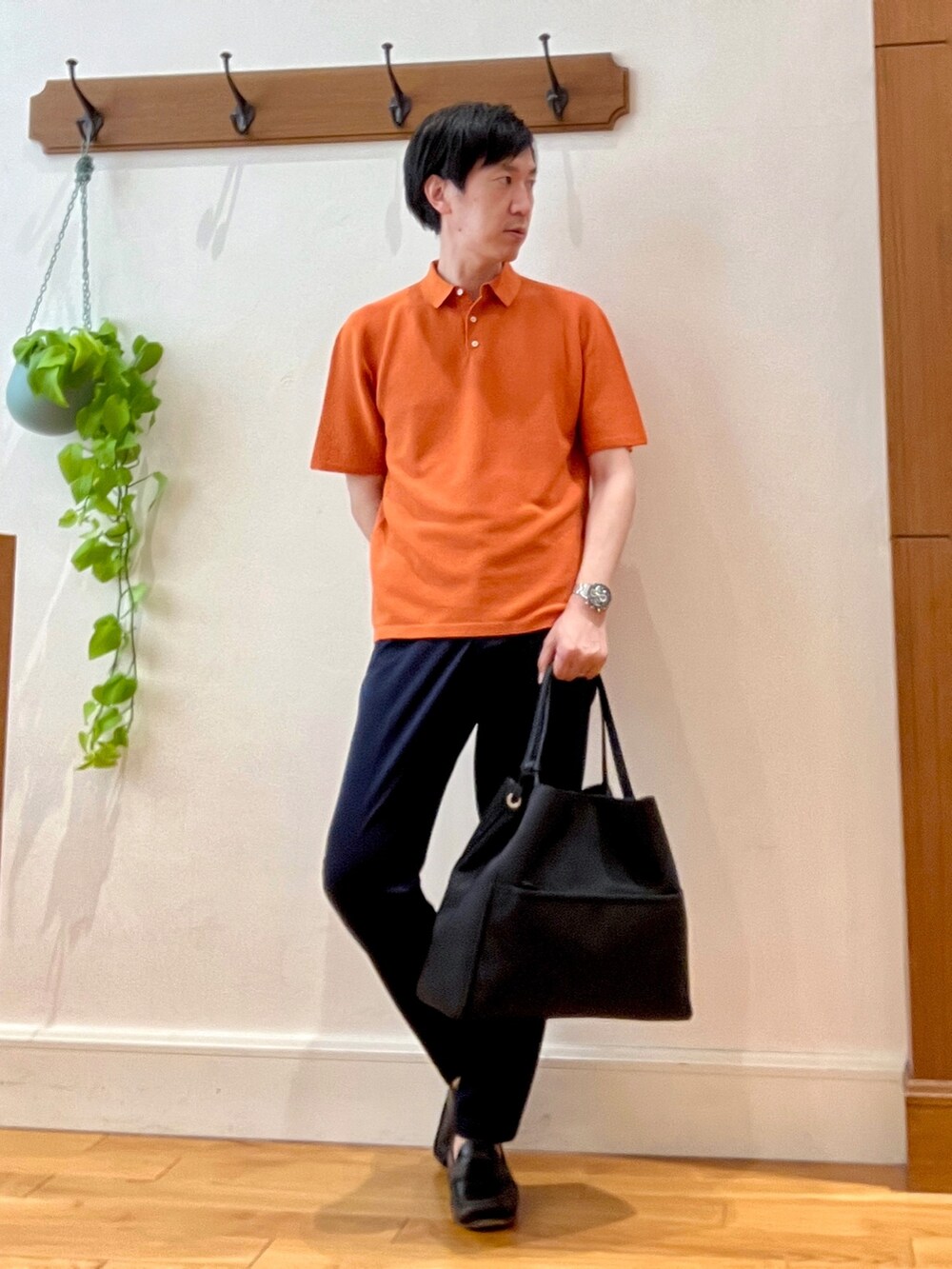 オレンジ系のポロシャツ、ブラック系のトートバッグ、ブルー系のその他パンツを着用したメンズの春コーディネートの4枚目の写真