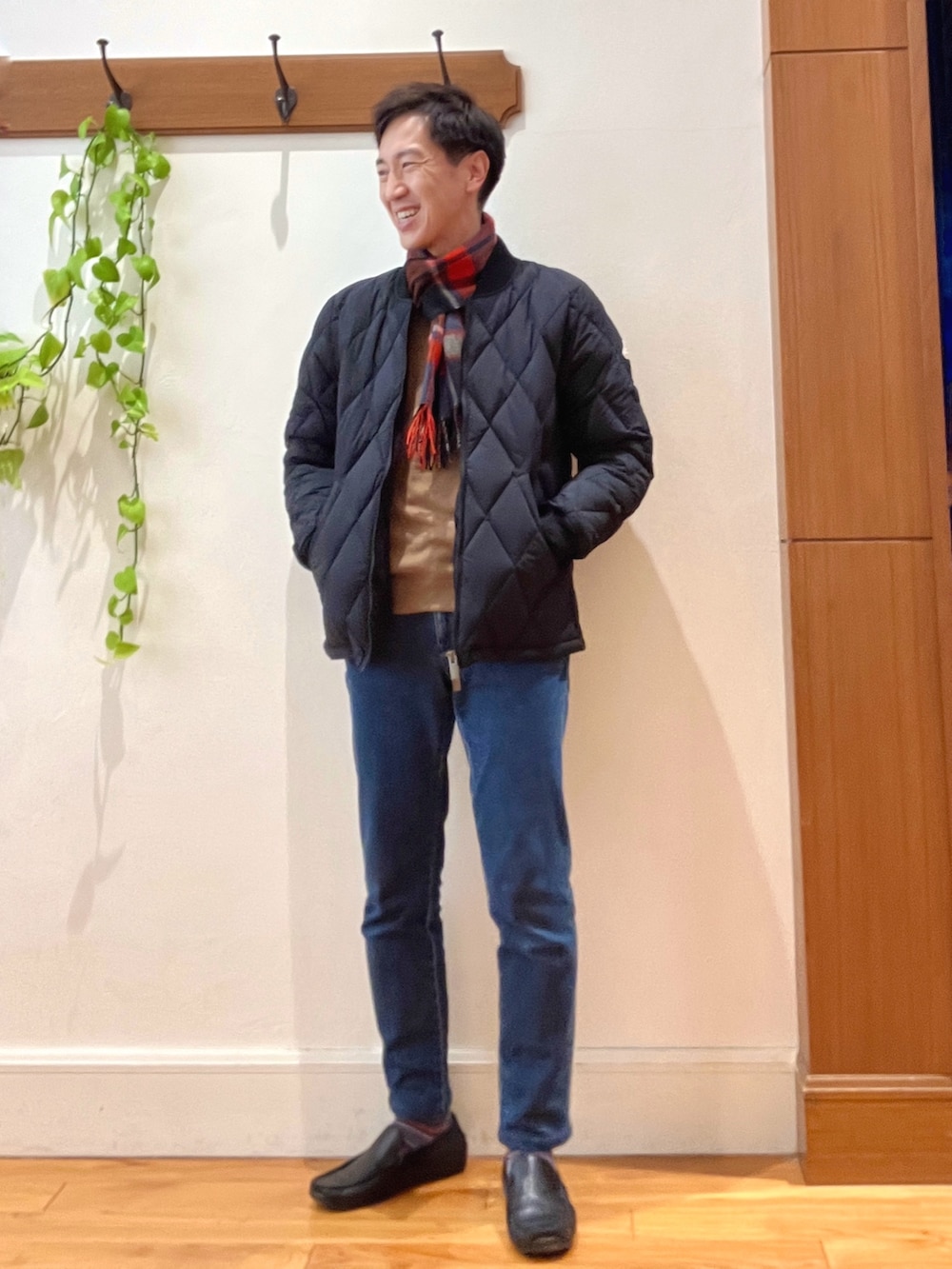 ブラック系のダウンジャケット/コート、ベージュ系のニット/セーター、ブルー系のデニムパンツを着用したメンズの冬コーディネートの2枚目の写真