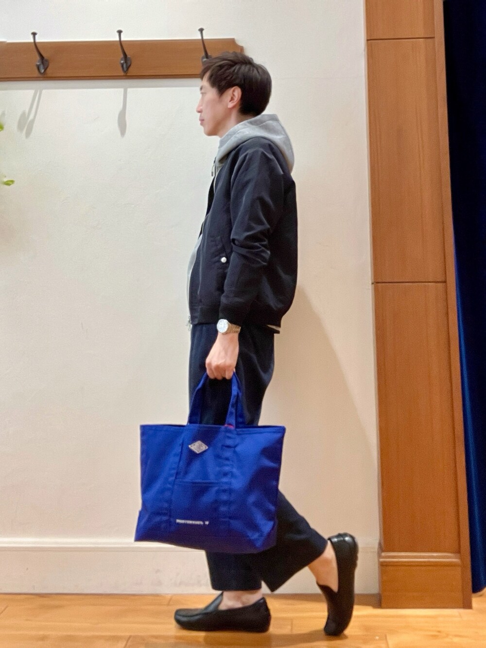 ブラック系のブルゾン、グレー系のパーカー、ブルー系のデニムパンツを着用したメンズの春コーディネートの2枚目の写真