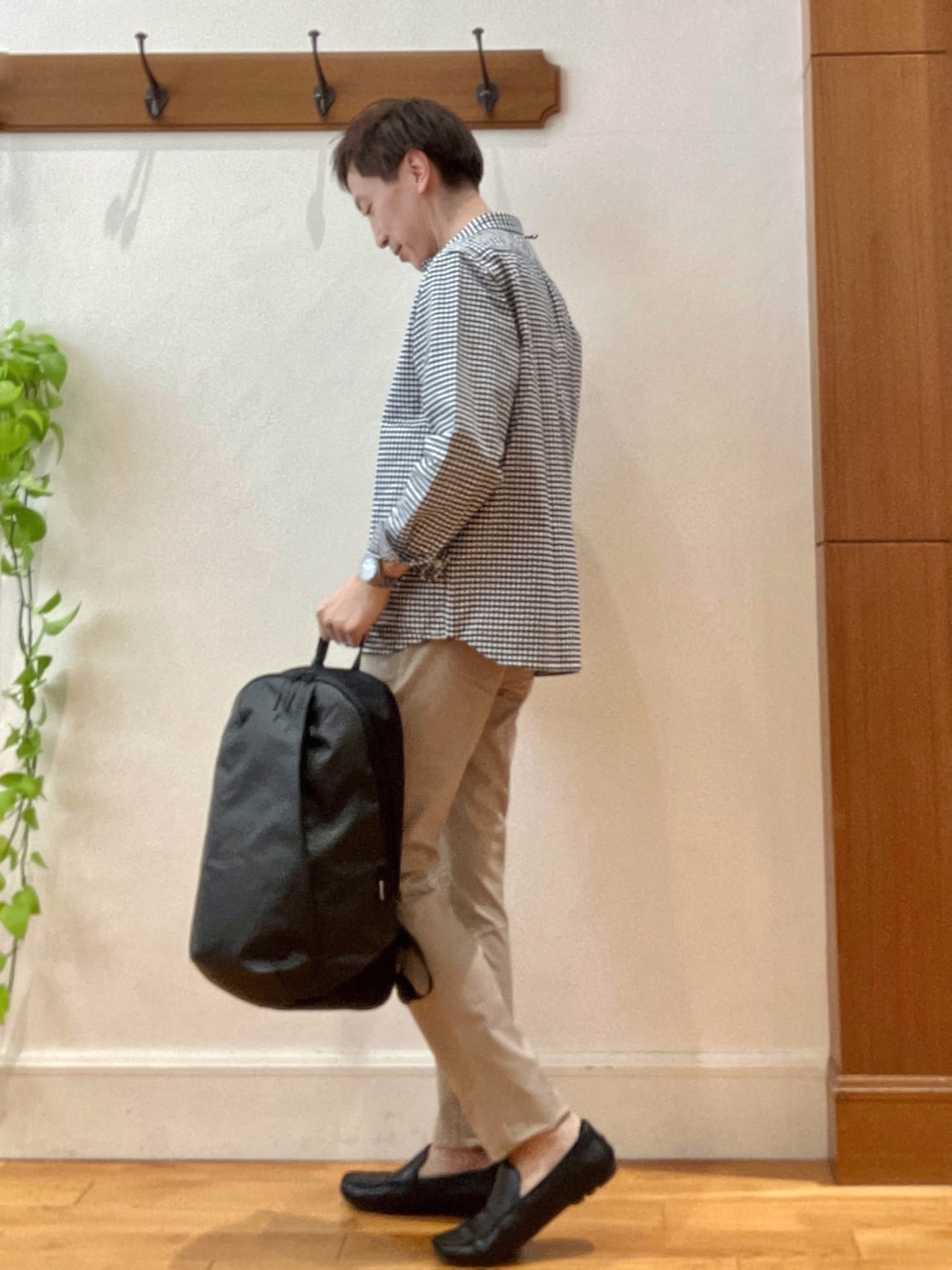 ブラック系のシャツ/ブラウス、グレー系のバックパック/リュック、ベージュ系のチノパンツを着用したメンズの春コーディネートの2枚目の写真