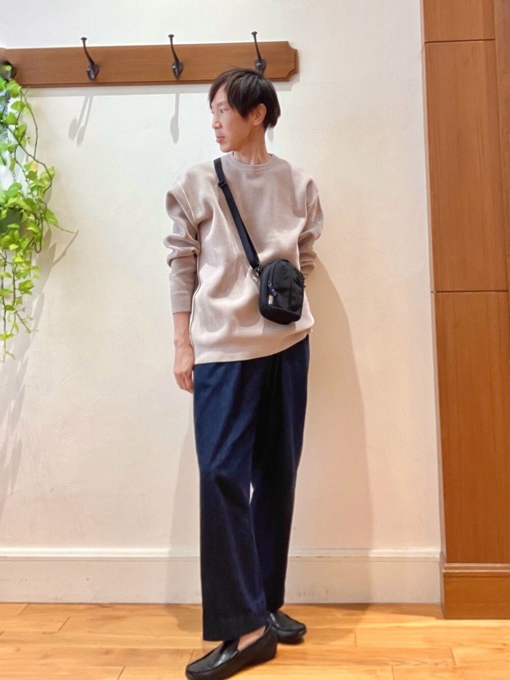 ブルー系のデニムパンツ、ブラック系のショルダーバッグ、ベージュ系のニット/セーターを着用したメンズの秋コーディネートの2枚目の写真