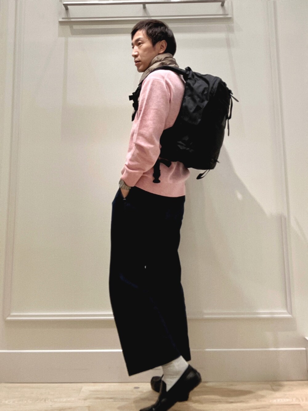 ピンク系のニット/セーター、ブラック系のバックパック/リュック、グリーン系のマフラーを着用したメンズの冬コーディネートの2枚目の写真