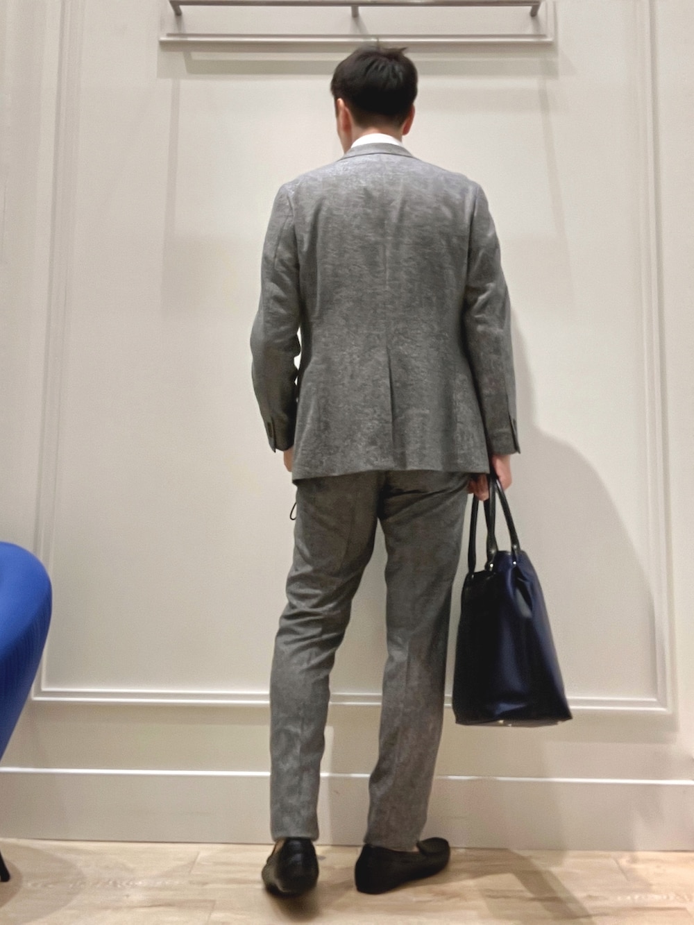 グレー系のテーラードジャケット、グレー系のスラックス、ブラック系のトートバッグを着用したメンズの秋コーディネートの4枚目の写真